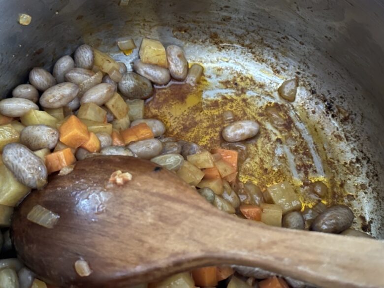 炒め物をしている鍋の底と豆、野菜と油