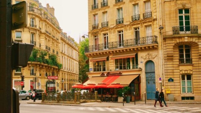 パリの街角にある高いビルと道路、カフェと歩行者