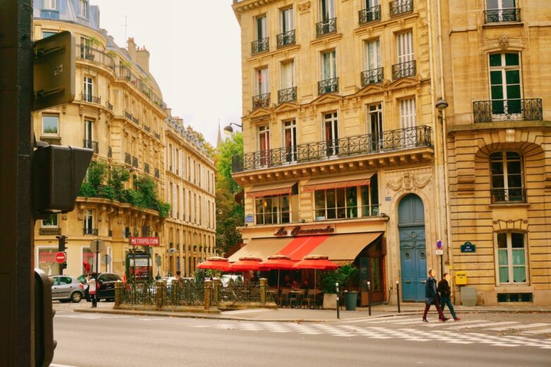 パリの街角にある高いビルと道路、カフェと歩行者